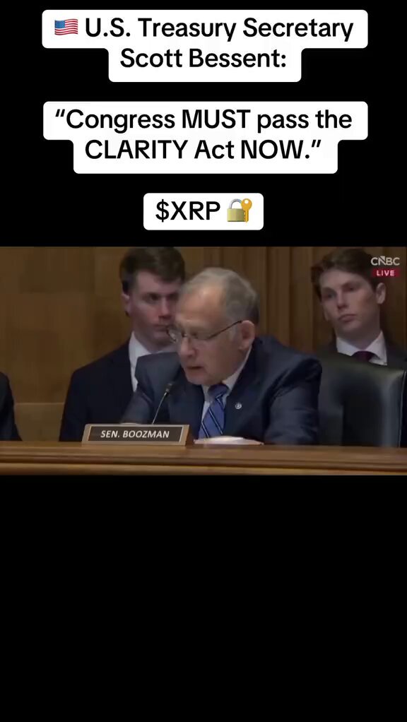 The image shows a man sitting at a desk, with a microphone in front of him. The text in the image reads "TRUMP PASSES LAW WITH @USTREasury AND @USSupremeCourt TO ALLOW U.S CITIZENS TO PRIVATELY PURCHASE XRP FROM AUTHORIZED EXCHANGES WITH U.S DOLLARS BEGINNING TODAY #XRP #xrpnews #xrpholders #100kviews". The man is likely a speaker or an expert discussing the new law, and he is using his microphone to address the audience.