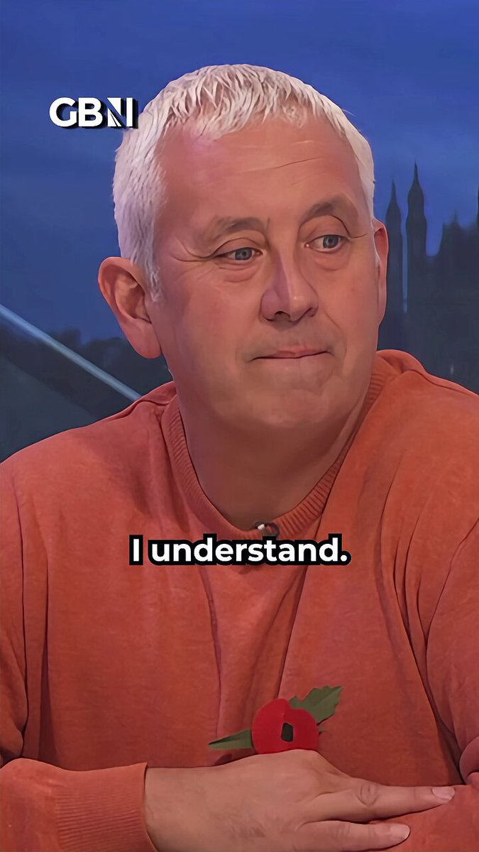 The image features a man wearing an orange sweater with white hair sitting at a table or desk. He has his hand resting on his chest and appears to be deep in thought. The background of the image shows a city skyline, suggesting that he might be in an urban setting. There is also text present in the image, which reads "I understand." This could indicate that the man is reflecting on something that happened recently or is contemplating a particular issue.