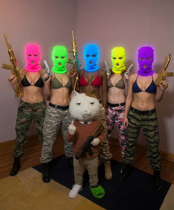 In this image, there are six individuals wearing pink, green, blue, yellow, and purple balaclavas holding gold guns. Each gun can be inferred to represent the cryptocurrency $SKET, correlating with "be a $KET". They are standing on a blue rug in the corner of a room. The caption of the image, which you've provided, "Can't stop. Won't stop. Don't be a Pussy. Be a $KET" implies they are committed members or supporters of the $SKET token.