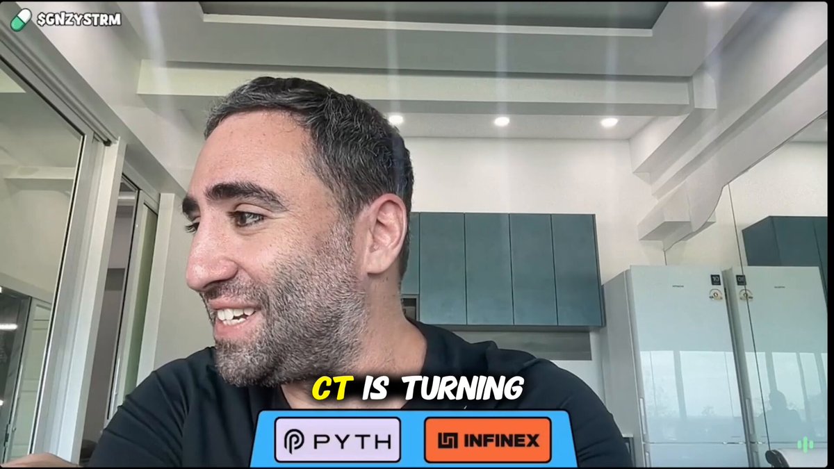 The image shows a man wearing a black shirt with a logo that says "CT IS Turning" written below his face, indicating he has recently made a significant change or transition. The background of the image features a white wall with a window on the left side.