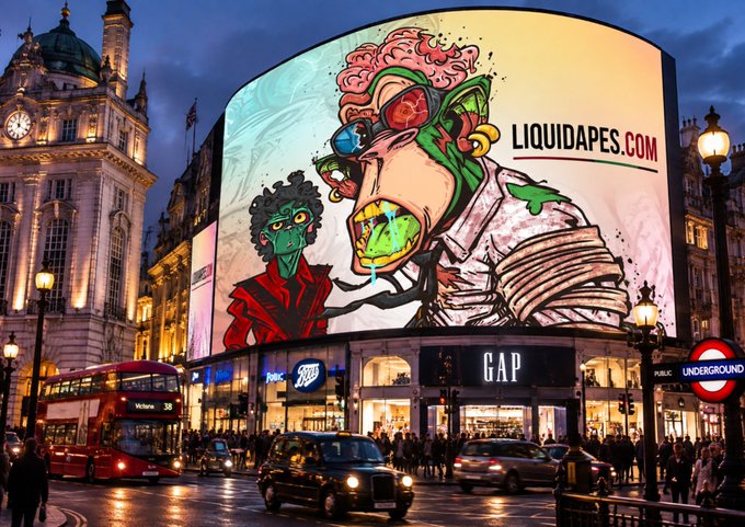 A vibrant, cartoon-style advertisement for LIQUIDAPES.COM displayed on a large curved billboard at Piccadilly Circus in London, featuring two grotesque green zombie-like characters with red splatter effects.