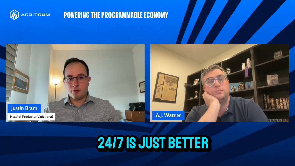 The image shows two men sitting at a desk, with their heads resting on their hands as they appear to be deep in thought or conversation. The background of the image features a blue banner that reads "24/7 programmable markets are just better." This suggests that the men might be discussing the benefits and advantages of 24/7 trading platforms for financial markets.