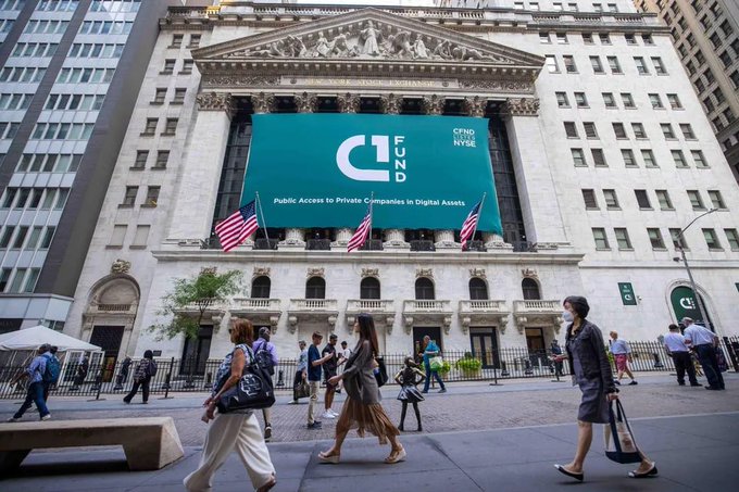 The New York Stock Exchange building with a large teal banner reading 'CFUND NYSE - Public Access to Private Companies in Digital Assets', with American flags and pedestrians visible in front.