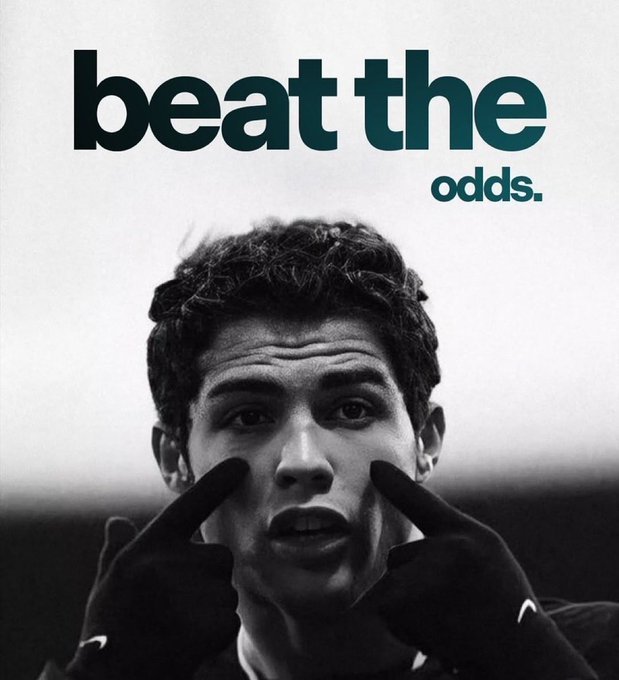 A black-and-white close-up of a young man pulling at his cheeks with gloved hands, paired with bold text reading "beat the odds." The image visually reinforces the motivational message to overcome challenges and make the day count.