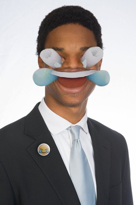 The image features a man wearing a suit, tie, and glasses with his eyes closed as if he's pretending to be sad or crying. He has a button on his lapel that says "i am buying LMAO!*". The man is also wearing a pin in his lapel, which reads "LMAO!". This combination of elements creates an amusing and lighthearted scene related to the post about LMAO!.