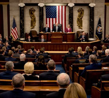 Members of Congress gather in the House Chamber, seated and facing the Speaker's rostrum where officials stand beneath the American flag and a presidential seal, as legislators prepare to debate and vote on the Bitcoin and Crypto Clarity Act with growing bipartisan support.