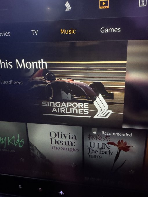 A digital media screen displays a Singapore Airlines sponsored content section featuring a Formula 1 car, with Olivia Dean 'The Singles' and JJ Lin 'The Early Years' music options visible below.
