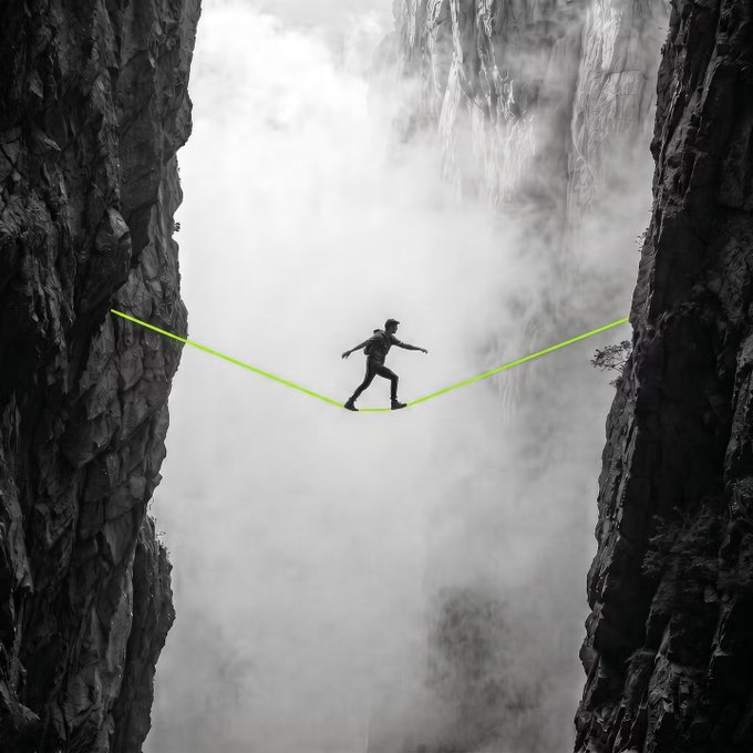 A lone figure balances precariously on a bright green slackline stretched across a deep, misty gorge between two sheer rock cliffs.

The image perfectly captures the post's "trenches" metaphor—evoking the dizzying, high-stakes, and precarious nature of navigating market volatility, where one wrong step means a steep fall.