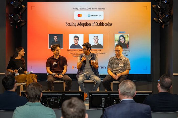 Four panelists sit on a stage at a conference discussing 'Scaling Adoption of Stablecoins' with 'Scaling Stablecoin Cross-Border Payments' between Mastercard and Borderless.xyz shown on the screen, featuring Deepanker Saxena and other speakers.