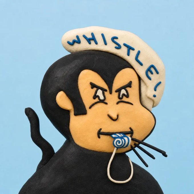 A decorative cookie featuring a cartoon monkey dressed in a black costume with a tail, blowing a whistle, wearing a white hat with 'WHISTLE!' written in blue icing.