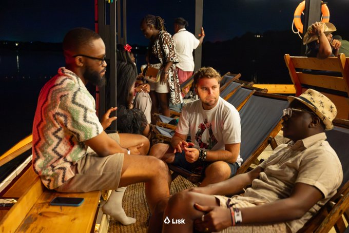Three men engage in conversation on lounge chairs at what appears to be a nighttime networking event, with the Lisk logo visible at the bottom of the image. The setting and Lisk branding suggest this captures a moment of community-building within the Web3 space, reflecting the post's reflection on emerging market partnerships and stepping away from LiskHQ.