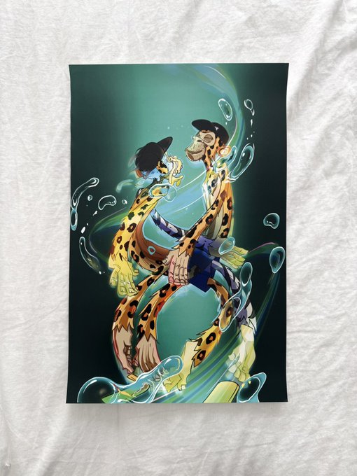 A poster displayed on a wrinkled white fabric showing a colorful anime-style illustration of two characters in animal print outfits embracing, surrounded by swirling teal water effects against a dark green background.