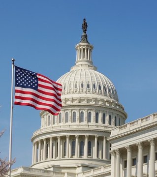 The U.S. Capitol dome stands prominently beneath a clear blue sky, with an American flag waving in the foreground—symbolizing the legislative process behind the newly released Senate Republicans' crypto Clarity Act draft bill.