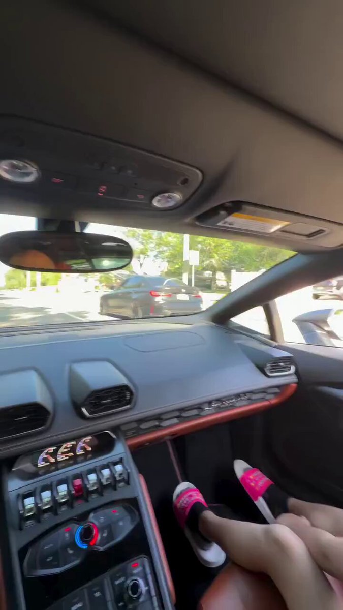 The image shows a person's hands inside a car, with their feet on the pedals of an automatic transmission vehicle. The car appears to be black, and there are other cars visible outside the window. A pink steering wheel cover can also be seen in the scene. The caption "Me in a few years when Gram makes me rich." suggests that the person might have been involved in some sort of online conversation or social media post about Gram, which could potentially be related to the car they are driving.

The image does not provide any information on what the post is about, but it seems to be connected to the car and its features. The focus should remain on the person's hands inside the vehicle rather than the content of the post.