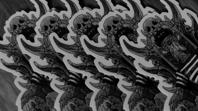 A row of identical black and white skull-themed stickers or patches with horns and tribal designs, fanned out across a dark surface.