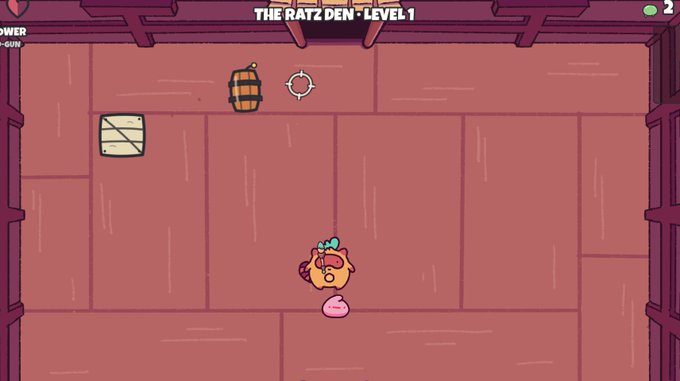 A screenshot of a 2D video game showing a cartoon character in 'THE RATZ DEN - LEVEL 1' with a barrel, target, and crate visible on a pink tiled floor.