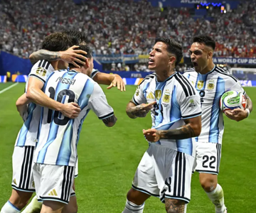 Argentina's soccer players, including one wearing jersey #22, celebrate together on the pitch, sharing an emotional group hug while one holds a match ball, capturing the team's passion as they play in a major tournament.