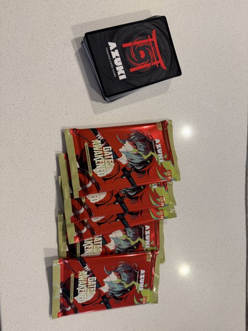 Four red 'Battle Hunters' snack packets and a black 'TOM' deck of cards laid out on a light-colored countertop.