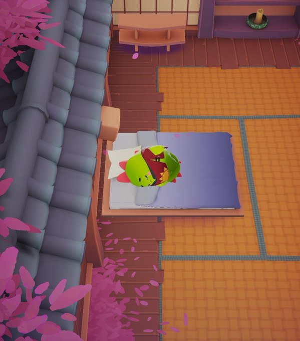 The image features a cartoon character, specifically a green frog or dragon, sitting on top of an orange bedspread with its eyes closed. The character appears to be sleeping peacefully. The surrounding area includes a pink wall and some plants, creating a cozy atmosphere for the creature's slumber.