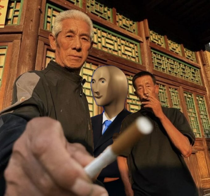 Two elderly men pose for a selfie with a surreal floating mannequin head wearing a blue tie between them, while one holds up a cigarette in the foreground.