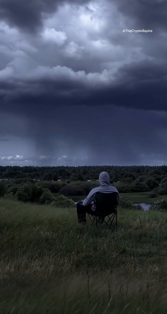 The image features a person sitting alone in a chair, looking out at a field with a cloudy sky above them. The scene suggests that they are contemplating or observing something beyond themselves. The caption provided seems unrelated to the main subject of the photo, which is the person and their surroundings.