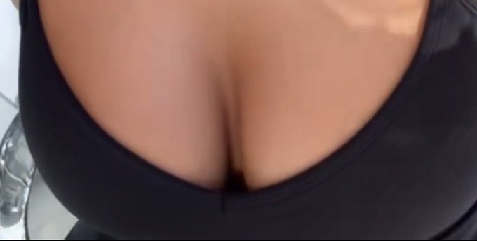 A person wearing a low-cut black top with visible cleavage, paired with a playful caption prompting viewers to guess the identity of a "Bitcoiner" with a prize of "an all expenses paid trip to the bottom of the bear market."