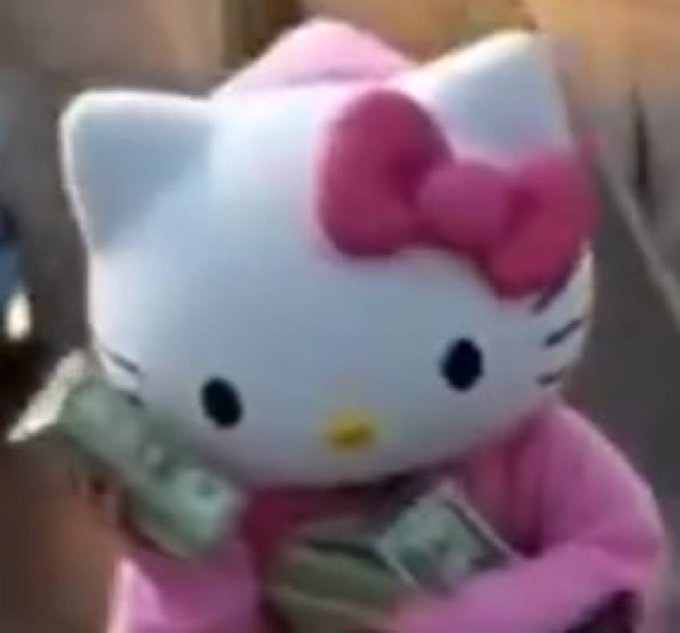 A blurry image of a Hello Kitty plush toy dressed in pink, holding stacks of cash.