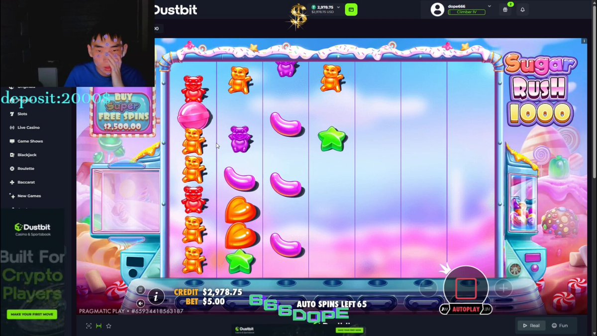 The image shows a person playing a slot machine game with a colorful background featuring candies and other sweets. The player's face can be seen as they interact with the game. The text in the image reads "@DustbitOfficial", which is likely a reference to the gaming platform or service being used by the player.