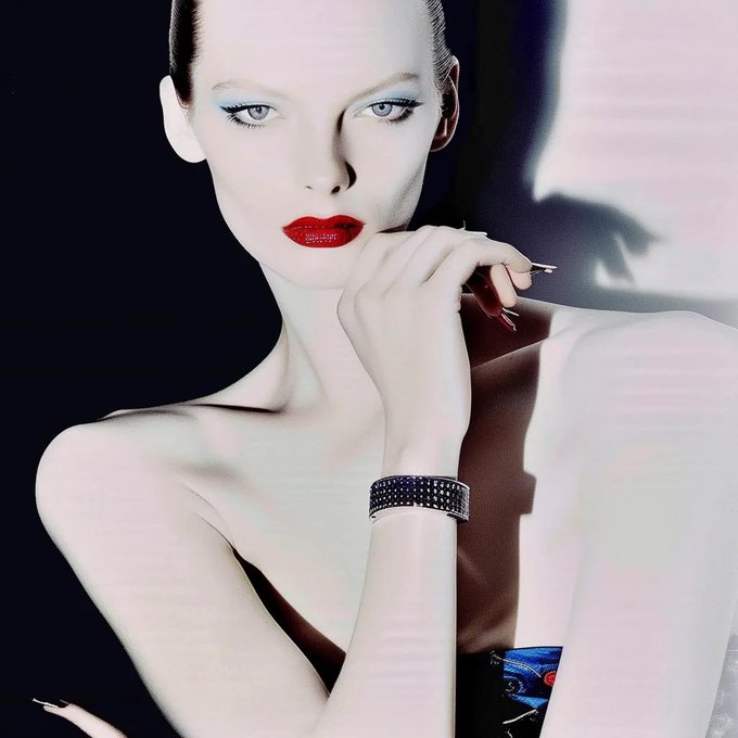 The image features a woman with red lipstick, wearing a black dress and posing for the camera. She has her hand resting on her chin while looking directly at the viewer. The background of the photo appears to be a dark color, which contrasts with the white shirt she is wearing. The image also contains text that reads "transient.xyz/nfts/base/0xa7 #2" and "#2".