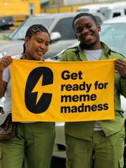 Two people hold up a yellow sign reading "Get ready for meme madness" alongside the CadeMarket (C) logo, promoting the upcoming meme madness campaign to spread brand awareness in person.