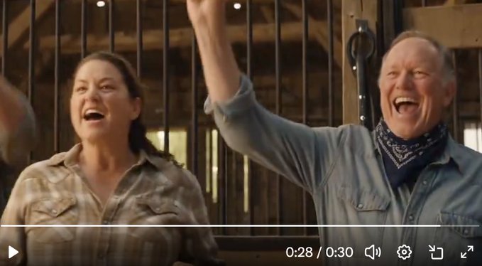 A video screenshot at 0:28/0:30 showing a man and woman laughing and cheering with arms raised in what appears to be a barn setting.