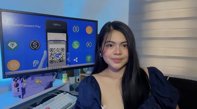 A young woman streaming or recording in front of a curved monitor displaying "WalletConnect Pay" with various cryptocurrency logos and a QR code showing a $56.00 payment screen.