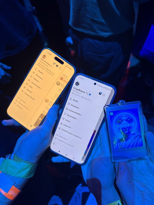 Two smartphones display the CryptoNueva app with sections like "Perfil," "Premium," "Comunidades," and "Listas," alongside a glowing blue acrylic Jesus charm, captured at a Blofin event celebrating the in-person meeting of crypto creators @follis_ and @milesdeutscher.