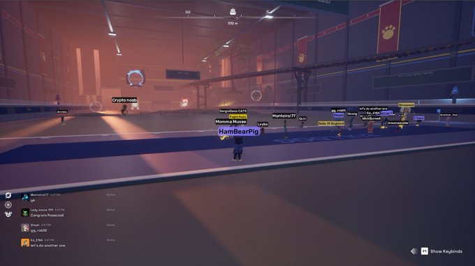A screenshot from a virtual multiplayer game showing several player avatars in a large industrial arena, with usernames like 'HamBearPig', 'Crypto_nono', and 'Monster77' visible above their characters.