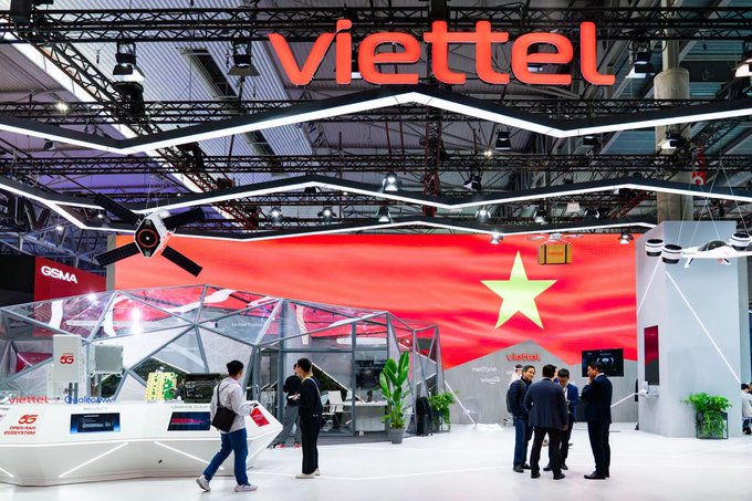 An exhibition booth for 'viettel' features a large red and yellow star, high-tech ceiling designs, and a 5G logo, with attendees walking around the displays.