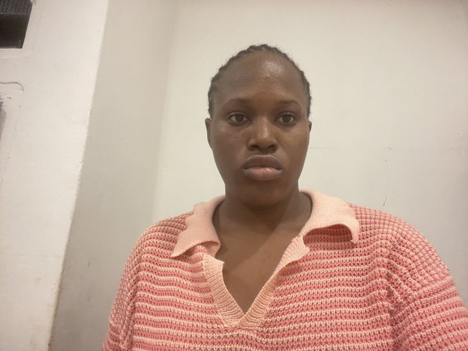 A portrait of a woman with short hair wearing a pink and white striped knit shirt, photographed against a plain wall.
