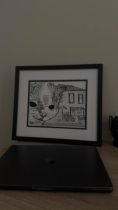 A framed black and white artwork sits above a closed MacBook on a wooden desk, the piece appearing to depict an abstract or pixelated scene. The caption alludes to holding onto the artwork from a previous crypto bull run as the market nears another potential peak, suggesting the artwork symbolizes memories from past market highs.