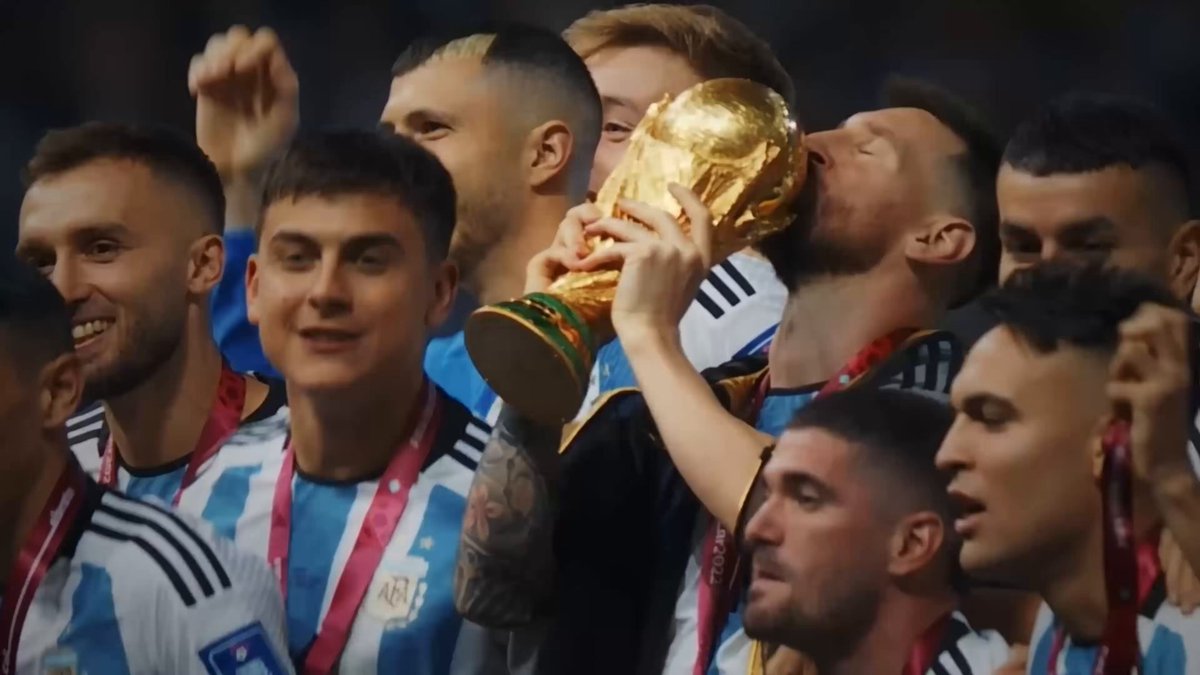 The image shows a group of soccer players celebrating after winning the World Cup, holding up a trophy as they raise their hands in victory. The team members are smiling and hugging each other, expressing their joy and satisfaction with the win. The photo captures this moment of triumph and camaraderie among the players.