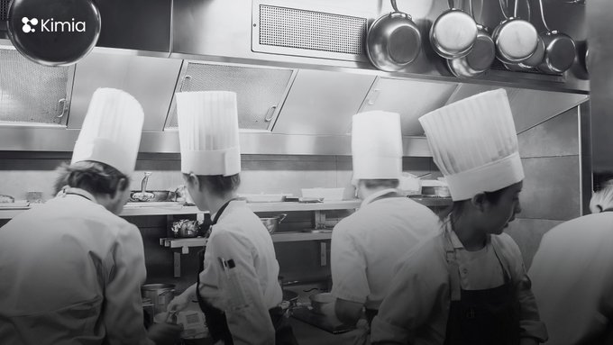 A black-and-white photo shows several chefs in tall white toques working in a stainless steel kitchen, with the Kimia logo in the upper left corner.