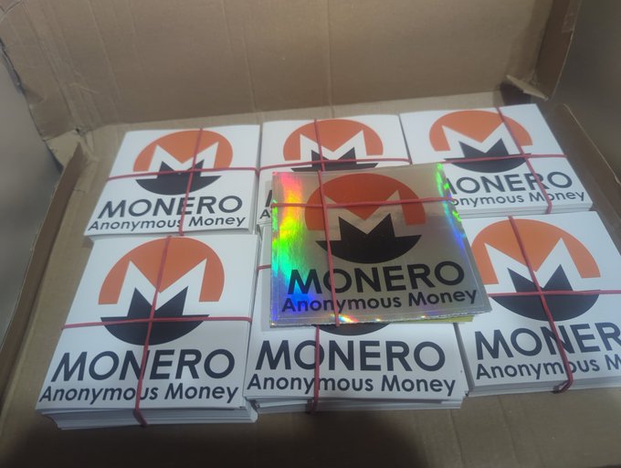 The image features a cardboard box filled with various Monero stickers. There are nine stickers in total, each displaying the Monero logo and the words "Monero Anonymous Money". The stickers are neatly arranged inside the box, showcasing their vibrant colors and unique designs. The text on the image reads "hi, Monero guerrilla marketing US team; where you at?" which could be a promotional message or an invitation for Monero enthusiasts to join the movement.

The post also mentions that there is a "Monero Anonymous Money" sticker in the box, suggesting that it might be related to Monero's anonymity feature. The image seems to be promoting Monero as a unique and innovative cryptocurrency with a distinctive identity.