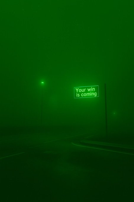 A dark, foggy green-tinted image of a street with a glowing sign that reads 'Your win is coming'.