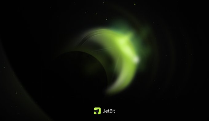 A dark space-themed teaser shows a faint green, aurora-like glow surrounding a large shadow, suggesting an imminent reveal. The JetBit name and logo appear at the bottom, reinforcing the promise that “you’ll know what” is coming today.