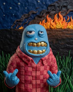 A blue-skinned cartoon character with gold teeth, wearing a red checkered shirt, makes a middle-finger gesture against a surreal backdrop of flames and a starry night sky. The image aligns with the post's focus on humorous, edgy Web3 NFT art projects like @just_t00ns, @Wackyville, and others highlighted for their degen aesthetic, cult-building humor, and low-supply 1/1 collections.