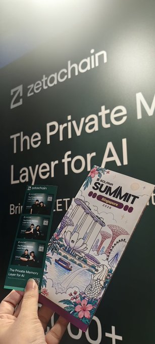 A hand holding a 'KCS SUMMIT 25 SINGAPORE' badge in front of a 'zetachain - The Private Memory Layer for AI' banner.