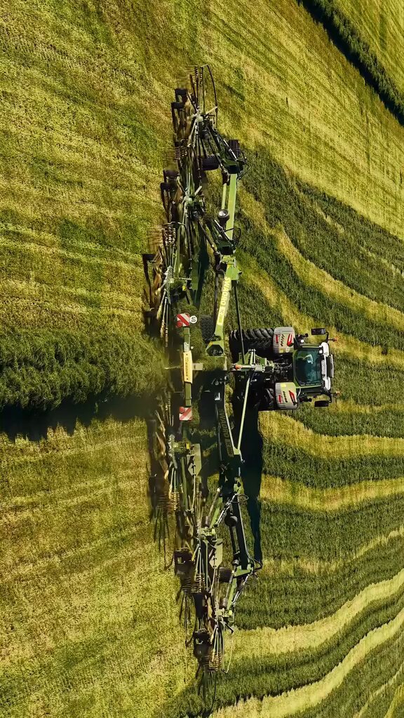 The image shows an aerial view of a field with a green tractor, possibly a combine harvester or lawn mower, working through the grass. The text in the image reads "Hey dude, the @bankrbot community created a coin to support your project. The fees of the coin are redirect to you." This message is related to the post because it appears that someone has created this coin as a form of support for the person who posted about their agricultural work or farming activities on social media platforms like Twitter and Instagram.