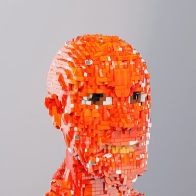 A sculptural LEGO portrait of a human head rendered in vibrant orange and white bricks with a skeletal, blocky face, matching the "Bricktopians" pixelated aesthetic referenced in the user's introduction.