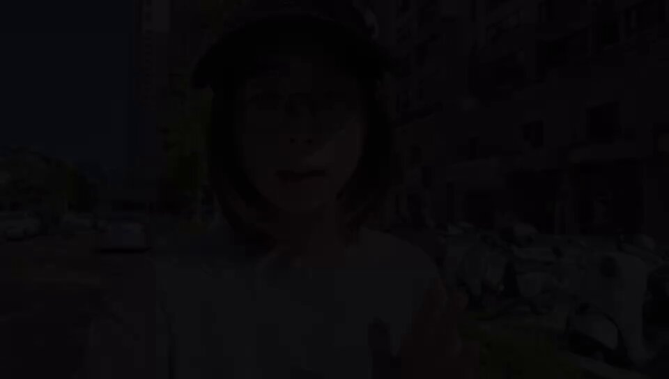 The image shows a woman wearing glasses, standing outside with her hand raised. The photo has been edited to make it appear as if she's speaking into a microphone or recording device. The caption below the image reads "那什么，我刚睡醒，太阳有点刺眼。".