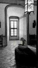 A black and white photograph shows a quiet interior space featuring a window, arched doorways, and a small sculpture resting on a stone surface, with hanging lanterns adding to the peaceful atmosphere. The image appears to be the artwork titled "Where Peace Rests," being promoted as a limited edition photograph (8 of 10 available) for 25 XTZ, with Adobe content credentials available for authenticity verification.