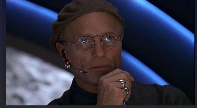 A man wearing a cap and headset with a contemplative expression listens intently, his ringed hand resting near his chin. The image's thoughtful pose connects to the post's point about naively trusting phones as the sole safeguard for bitcoin holdings.