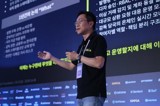 Chairman Seo Sang-min delivers a keynote on "Asian Onchain Finance, the Start of the Infrastructure Race," gesturing while speaking at a conference with sponsor logos from companies like KIMPGA, tenchum, OPTABRM, coinone, and Surf Futures visible on the stage backdrop. The image visually supports the post's reference to his leadership in discussing onchain financial infrastructure across Hong Kong, Southeast Asia, and JPYC initiatives.